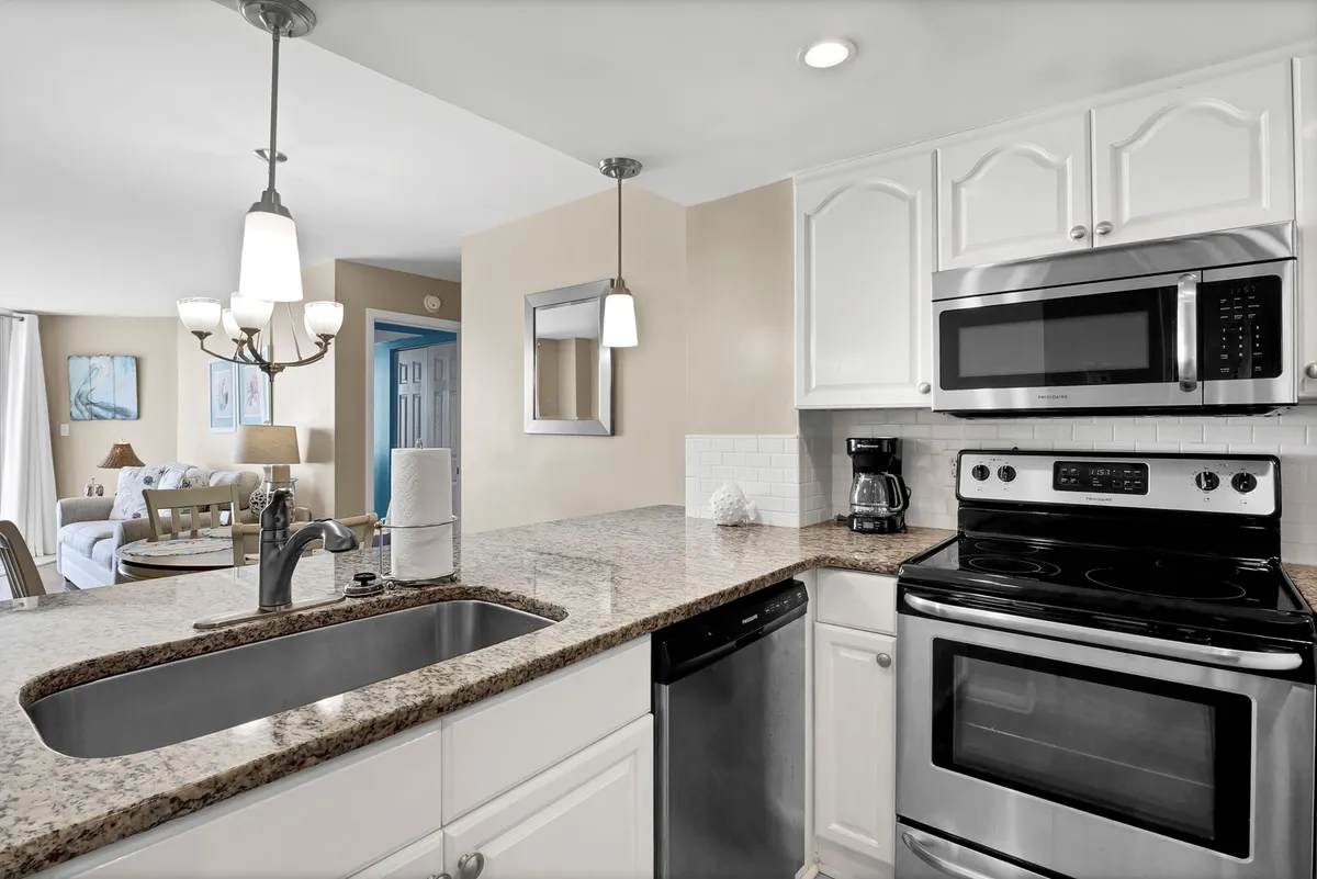 A spacious kitchen island with a granite countertop takes center stage, surrounded by stainless steel appliances and illuminated by pendant lighting. The warm, welcoming atmosphere is perfect for meal prep, entertaining, or spending time with family.