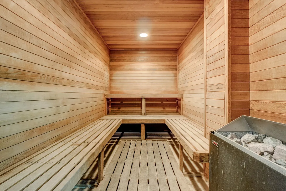 A serene sauna interior featuring wooden benches and a stone heater, providing a tranquil environment for relaxation and post-workout recovery.