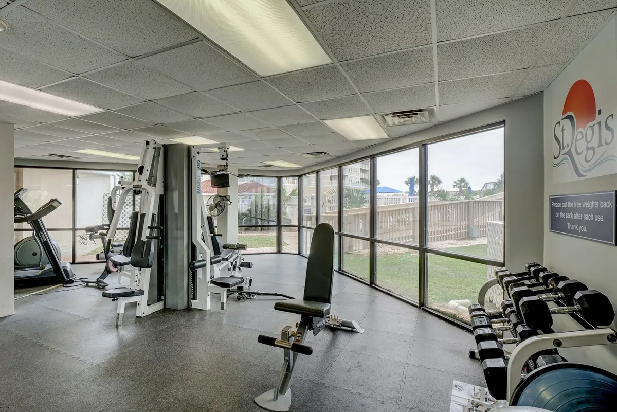 A modern, energizing fitness center with diverse exercise equipment, large windows for natural light, and mats for group classes. The space feels motivational and ideal for guests wanting to exercise or socialize during their stay.