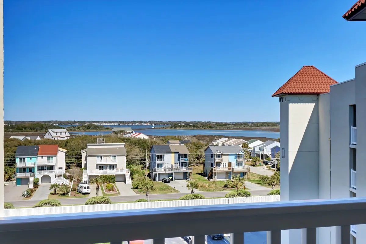 A serene balcony view overlooking a sparkling waterway with colorful houses and a bright blue sky. The scene suggests relaxation and inspiration, perfect for taking breaks or transitioning between work and leisure.